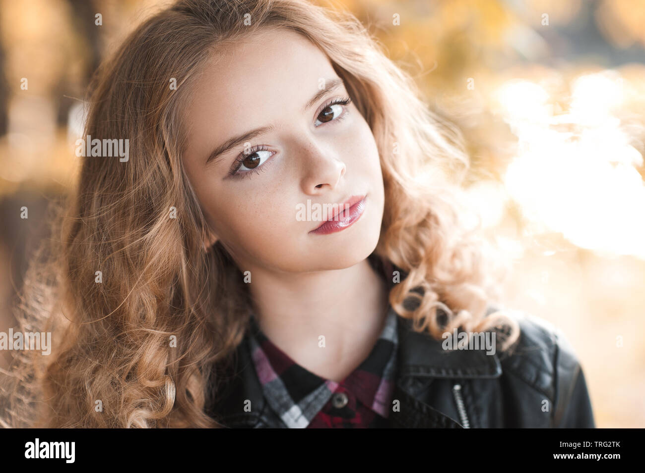 Belle blonde adolescente 12-14 ans portant blouson de cuir à l'extérieur. En regardant la caméra. Saison d'automne. Banque D'Images