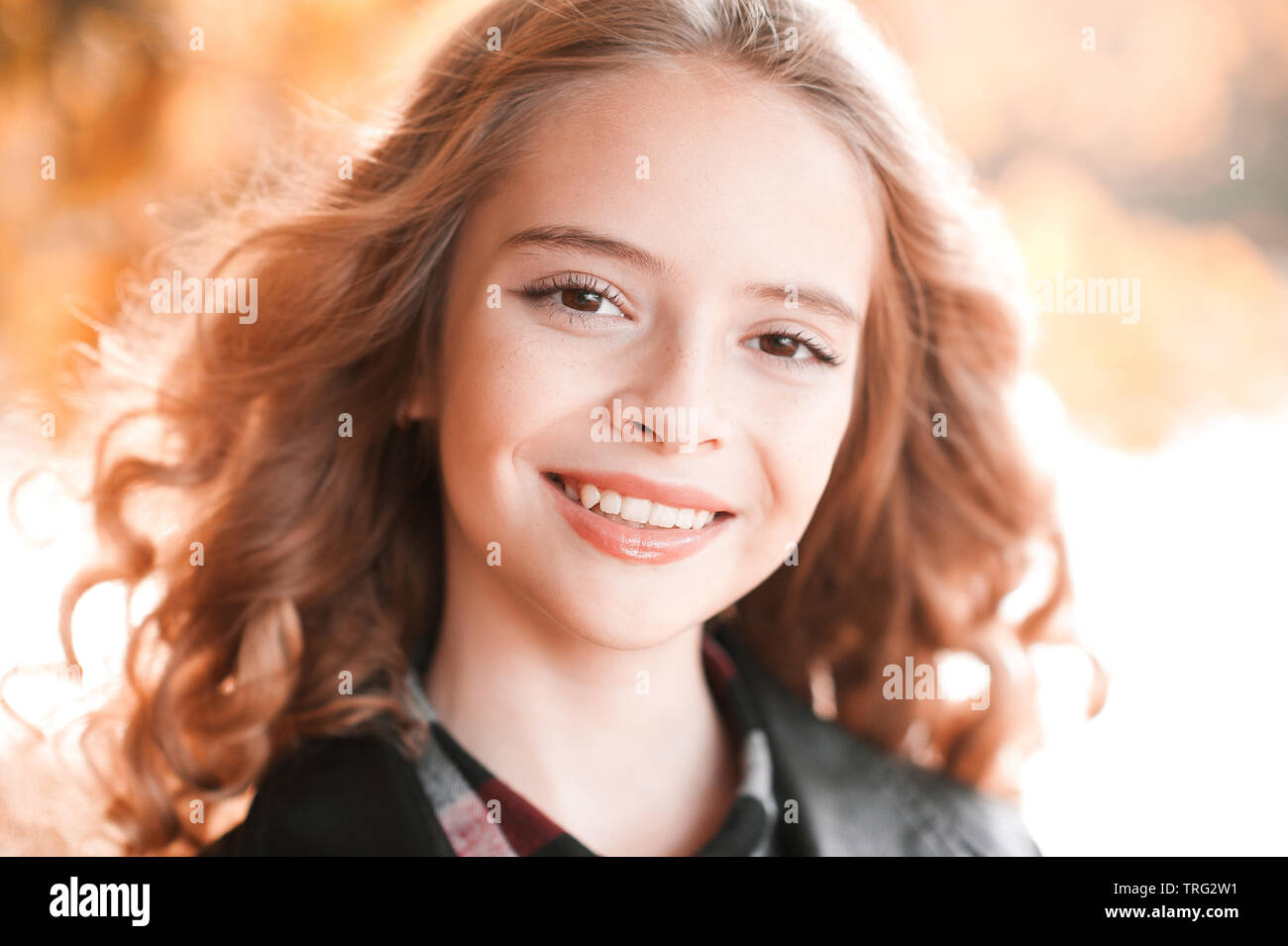 Closeup portrait of teenage girl automne 13-14 ans smiling over feuilles jaunes à l'extérieur. En regardant la caméra. Banque D'Images