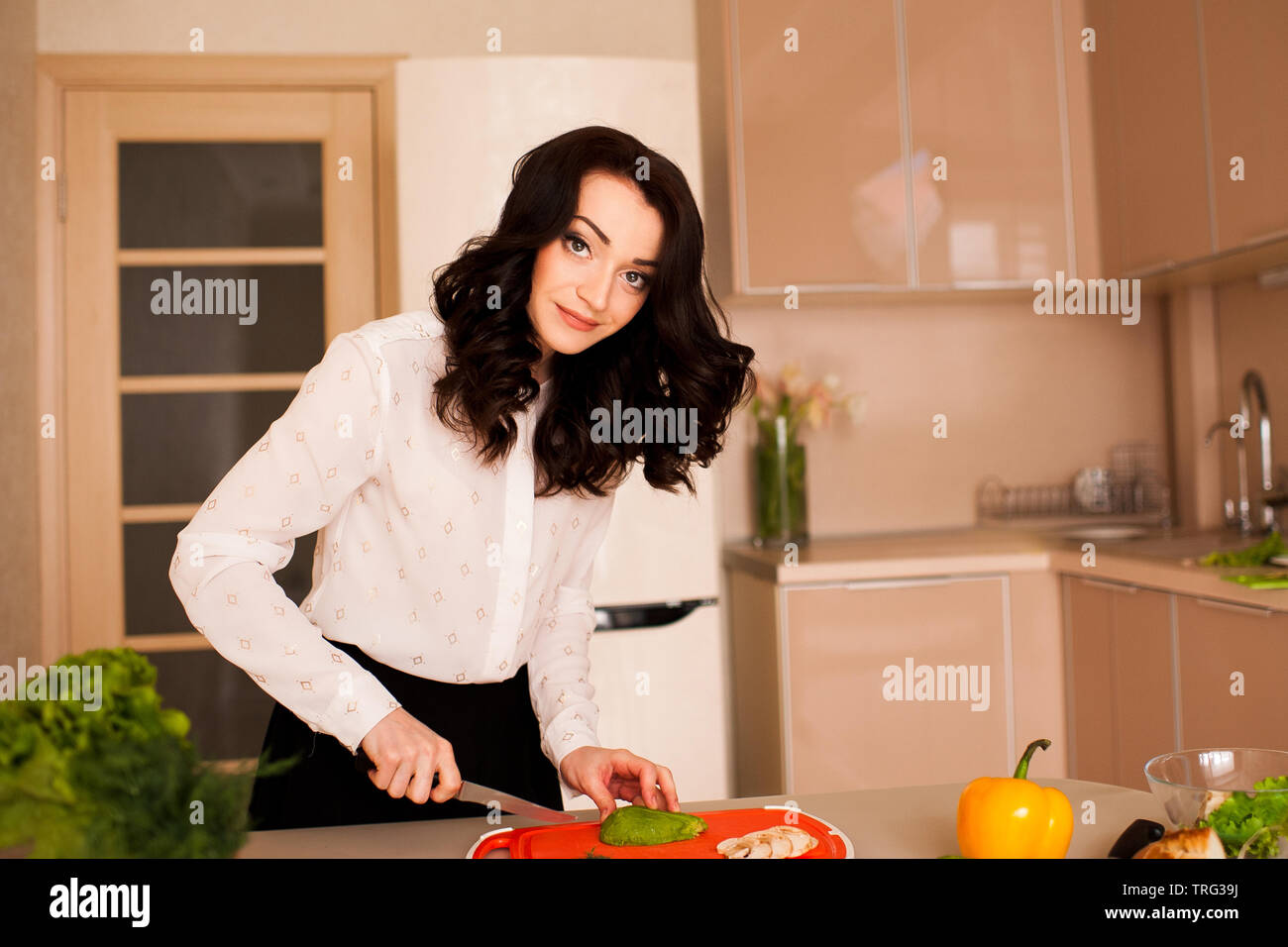Belle femme 24-29 ans avec salade cuisson des légumes frais dans la cuisine. En regardant la caméra. Mode de vie sain. Banque D'Images