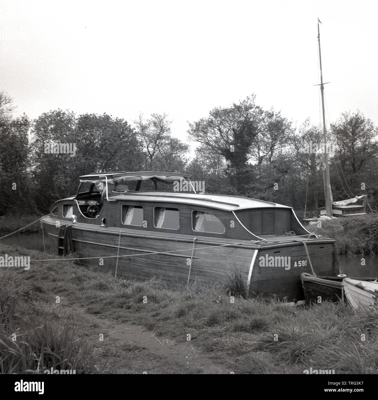 Années 1950, historique, un homme sur un bateau de croisière en bois, amarré le long d'une rivière sur la Tamise près de Oxford, Angleterre, Royaume-Uni. Banque D'Images