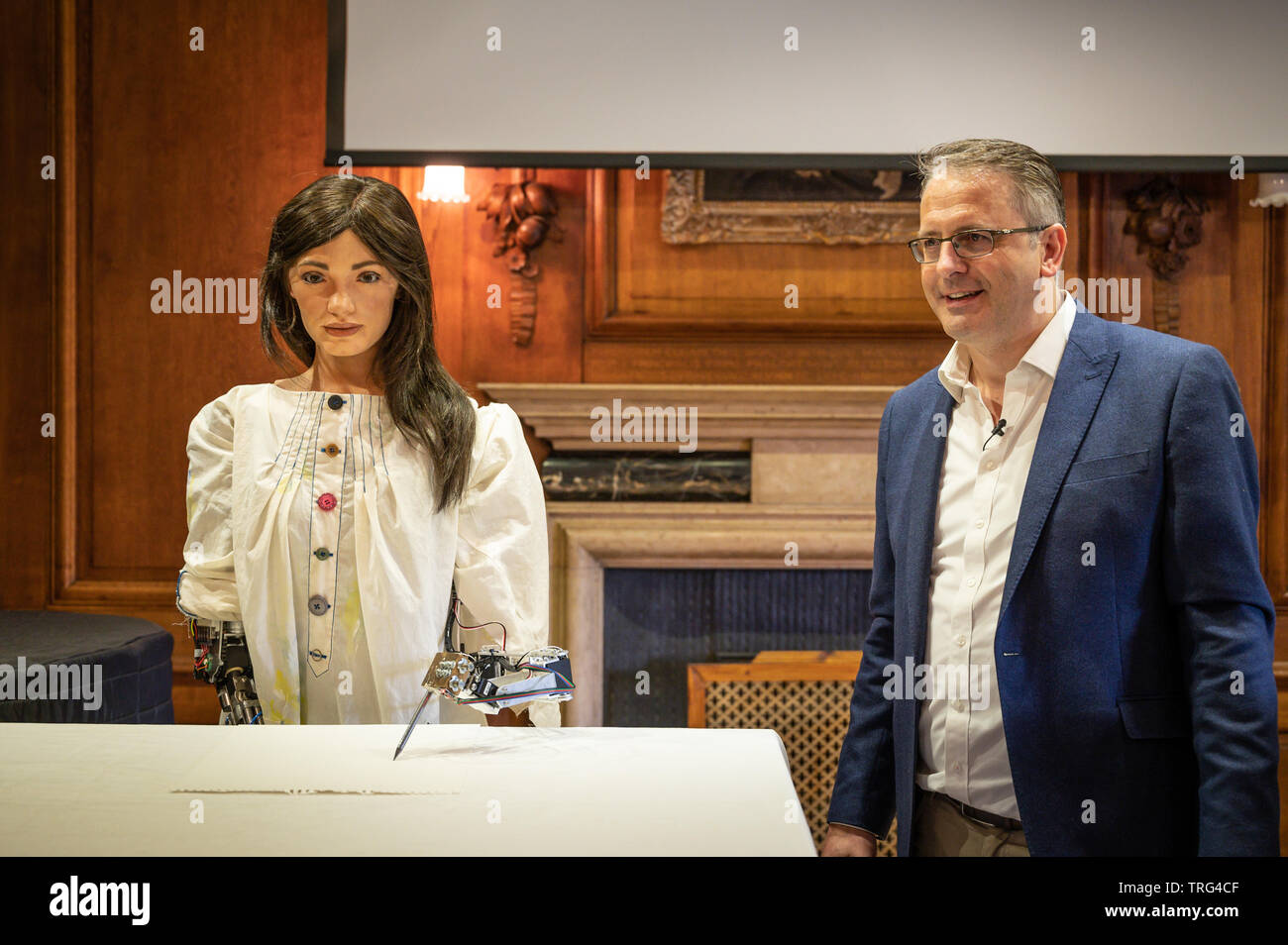 Oxford, UK. 5 juin, 2019. Le premier artiste robotique est dévoilé à Lady Margaret Hall, à Oxford. Le robot, appelé Ai-Da après Ada Lovelace qui a été la première femme programmeur informatique, l'invention d'Aidan Meller (en photo avec Ai-Da) qui gère les galeries à Londres et Oxford. L'IA utilise des algorithmes personnalisés pour analyser les visages humains et d'autres scènes et créer des pièces artistiques fondées sur ces derniers. Le croquis au crayon que le robot crée sont alors transformées en peintures complète par l'application de peinture par les assistants. Crédit : Andrew Walmsley/Alamy Live News Banque D'Images