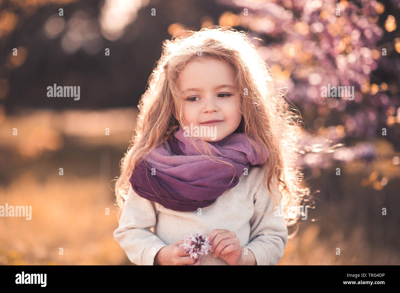 Mignon bébé fille 3-4 ans holding flower portant des vêtements élégants à l'extérieur. Banque D'Images