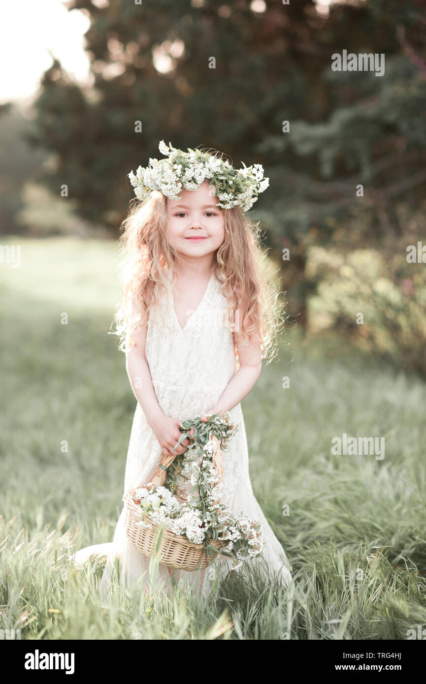 Sourire petite fille de 3-4 ans holding basket avec des fleurs à  l'extérieur. Le port de couronne de fleurs. En regardant la caméra.  L'enfance. L'élégance Photo Stock - Alamy