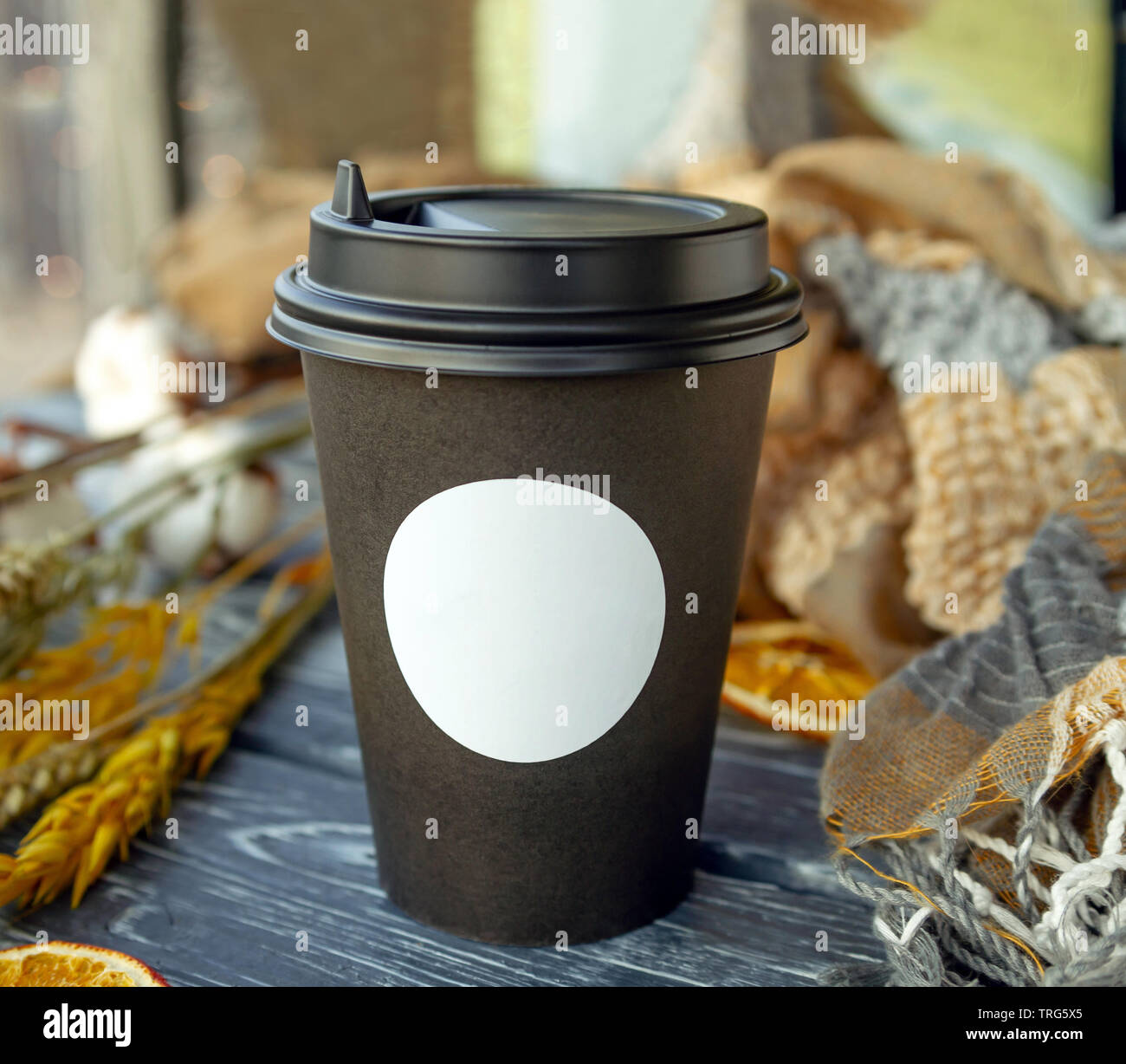 Une tasse de café en papier est sur la table avec des céréales et des épillets de tranches d'oranges séchées sur une journée ensoleillée Banque D'Images