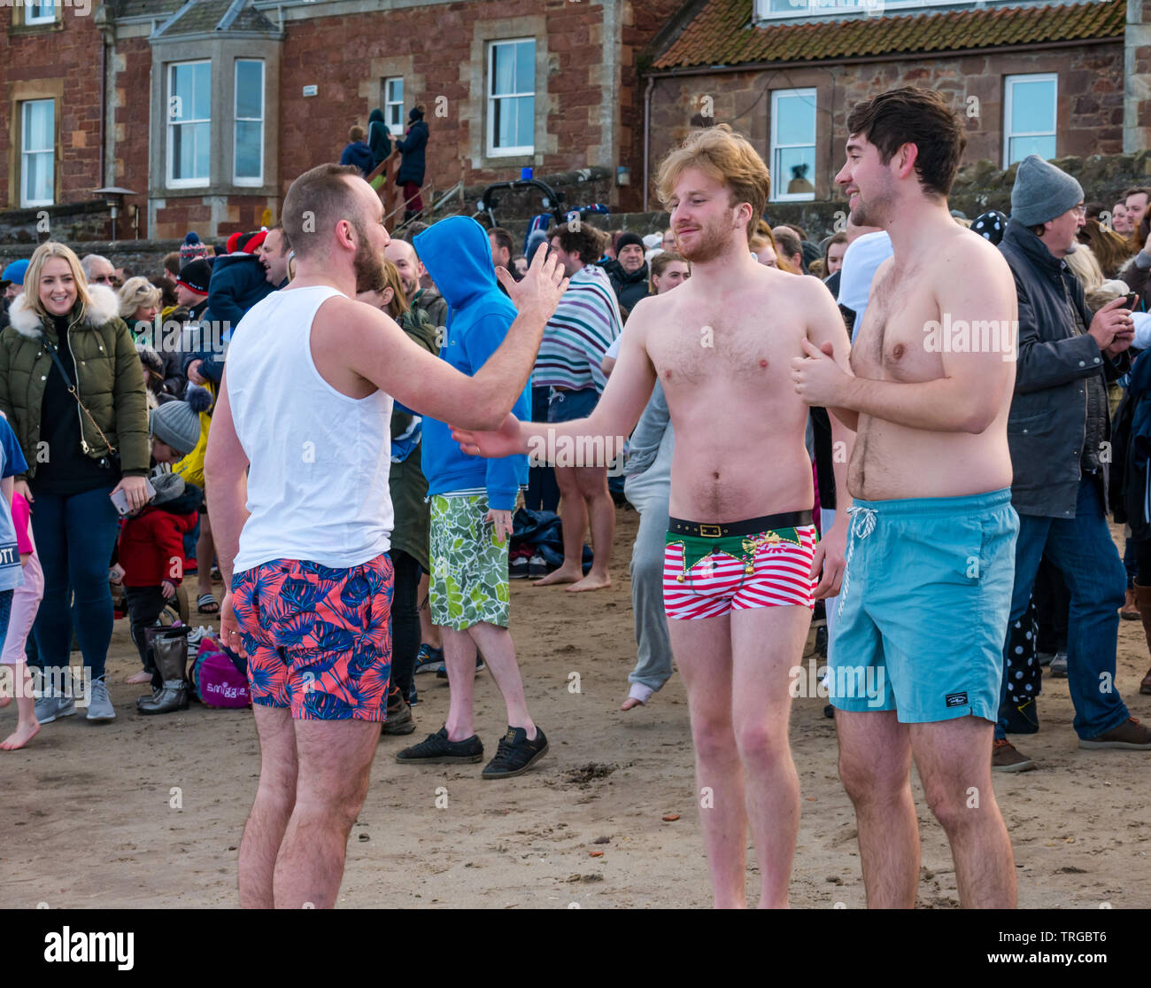 Loony Dook, le jour de l'An : Les gens braves de l'eau froide, West Bay, Firth of Forth, North Berwick, East Lothian, Scotland, UK. Les jeunes hommes en maillot de bain Banque D'Images