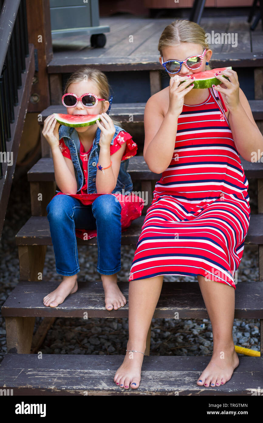 Deux filles mangeant du melon d'eau dans le lac tahoe un jour d'été portant rouge tandis que et bleu pour la fête de cour du 4 juillet. Banque D'Images