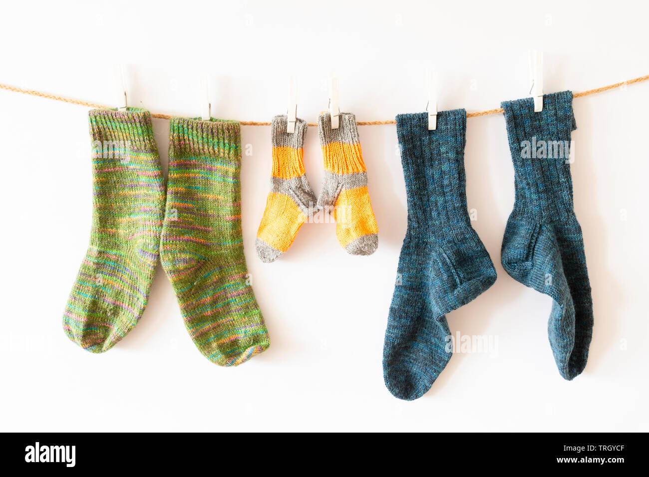Plusieurs paires de chaussettes de laine colorés de différentes tailles, suspendu à une corde avec fond blanc Banque D'Images