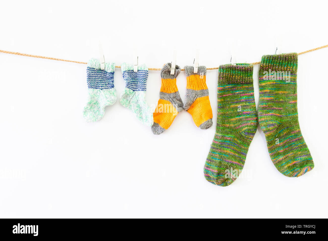 Plusieurs paires de chaussettes de laine colorés de différentes tailles, suspendu à une corde avec fond blanc Banque D'Images