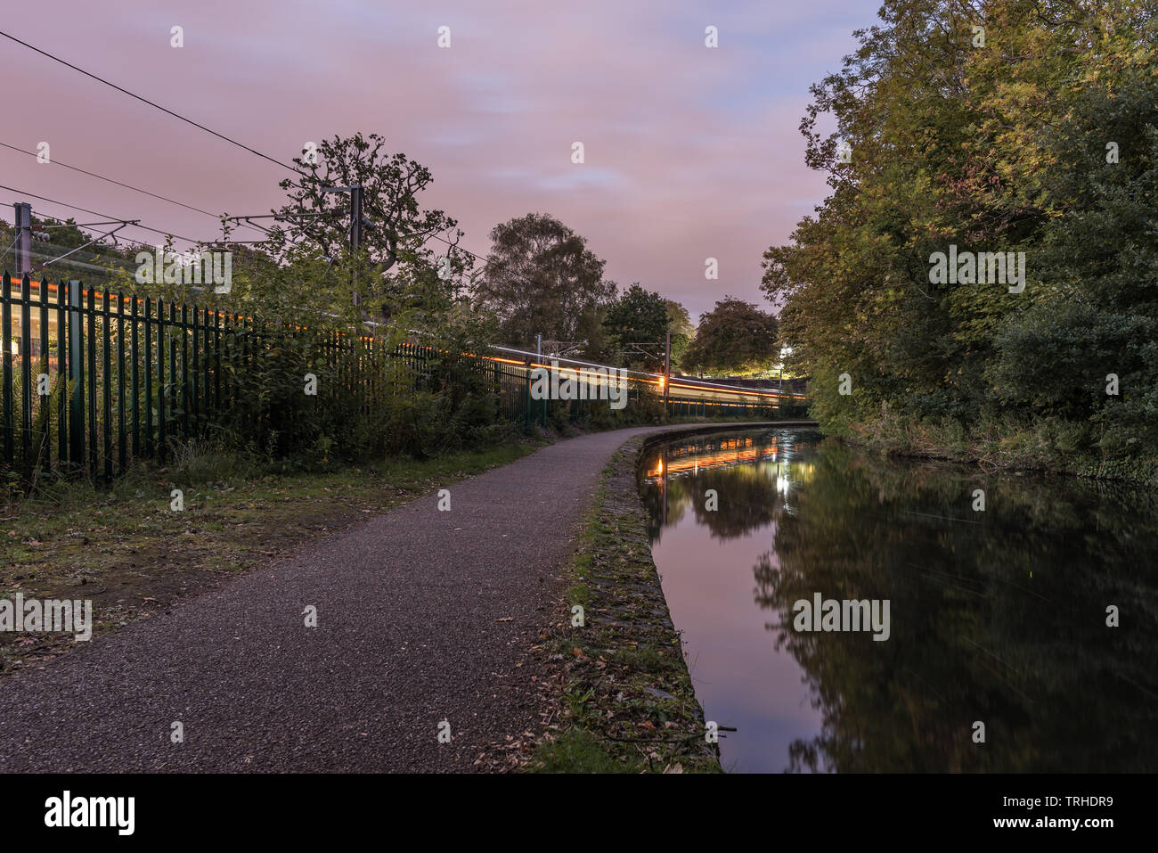 Worcester à Birmingham Canal, en Angleterre, UK. Le sentier le long du canal, avec un train en passant le long de côté. Le ciel commence à foncé Banque D'Images