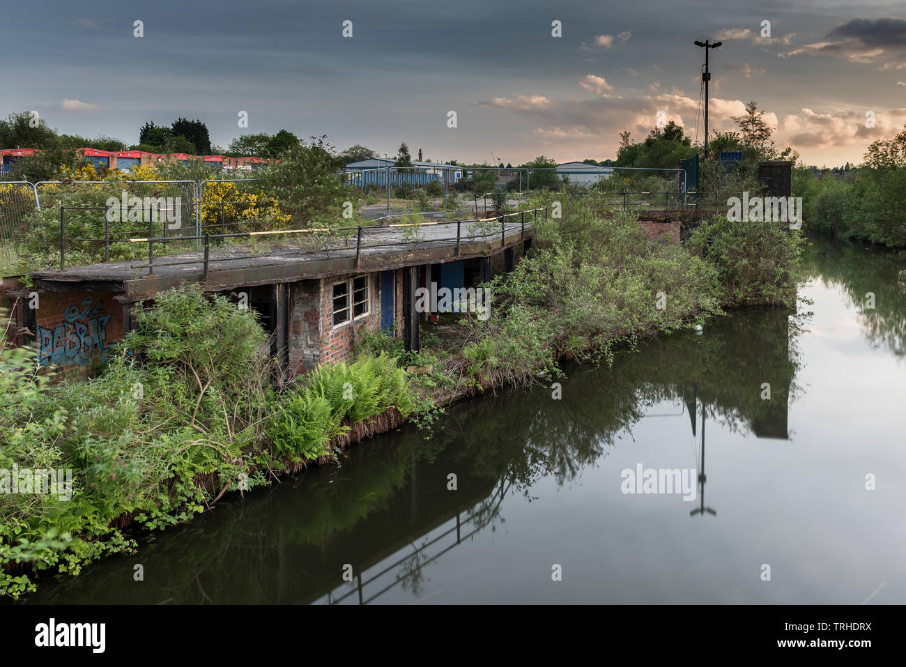 Un vieux, de l'épave, bâtiment, à côté d'un canal calme, couvert de feuillage, situé dans une friche urbaine, parle de l'eau très toujours, à Birmingham, E Banque D'Images