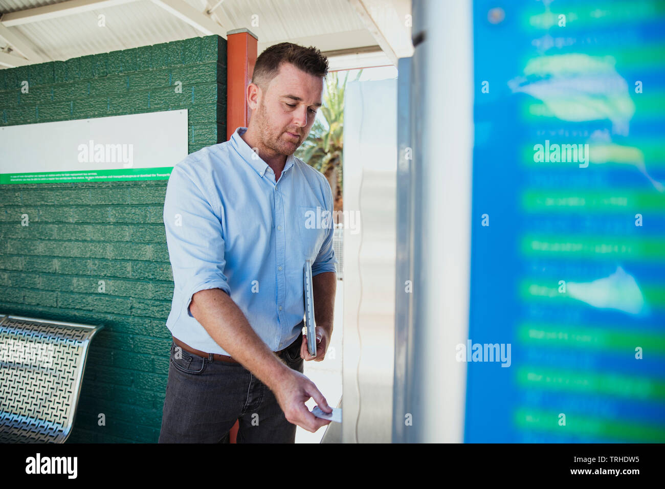 Un côté à la prise d'un mid-adult businessman acheter un billet de train pour commencer son trajet au travail. Banque D'Images