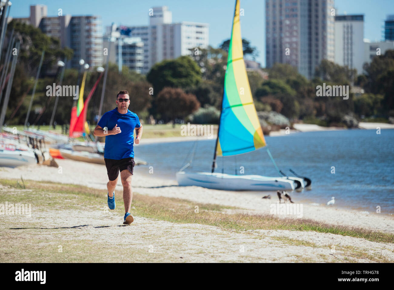 Un front à la prise d'un caucasian mid-adult man jogging sur la plage par une chaude journée d'été à Perth, Australie. Banque D'Images