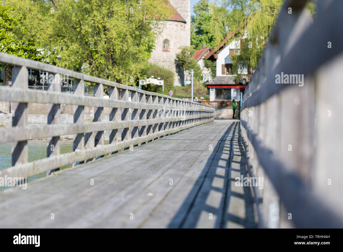 Low angle view of a landing stage / pier au lac Ammersee. Face à terre. Rampes en bois sur la gauche et droit. Arbres et maisons en arrière-plan. Banque D'Images