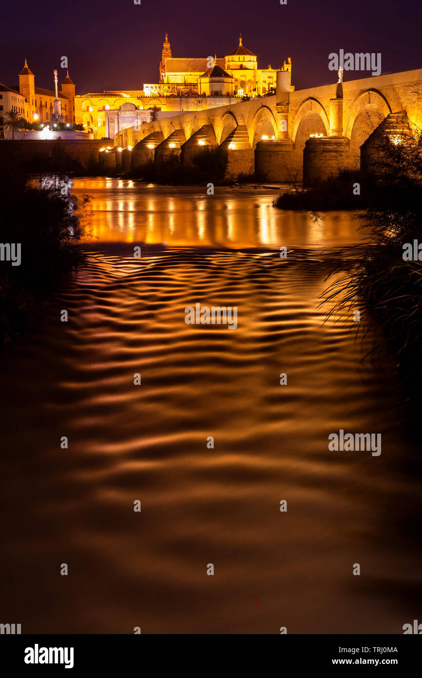 Pont Romain de pierres anciennes éclairées dans la nuit de la cathédrale Mezquita (Mosquée Maure) sur le contexte à Cordoba, Espagne Banque D'Images