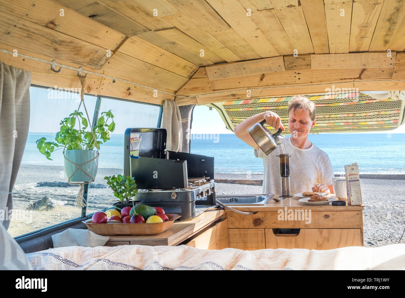 Prendre le café du matin avec un aeropress dans un camping-car à la plage, Nouvelle-Zélande Banque D'Images