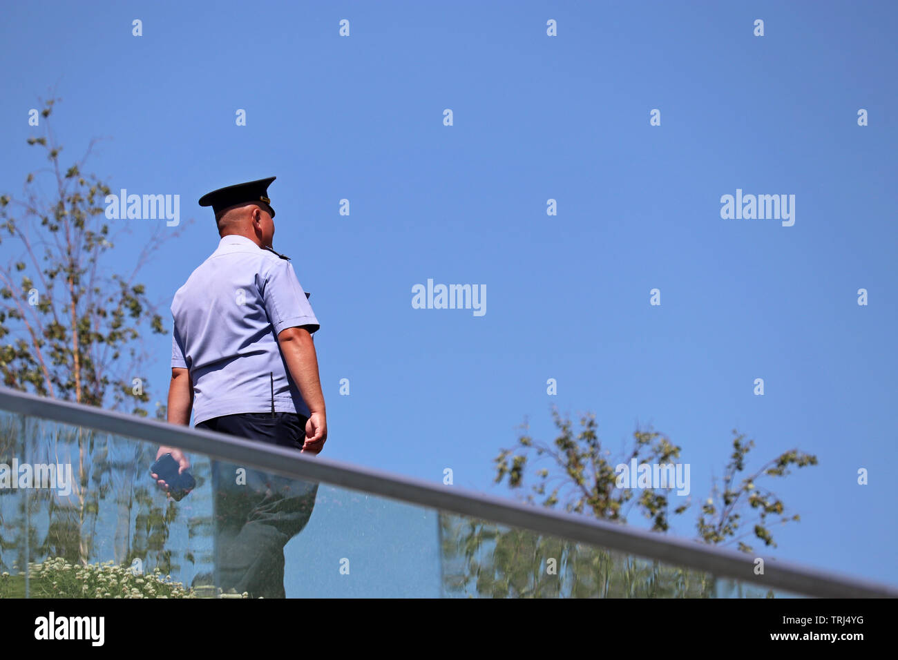 Policier patrouiller dans un parc d'été. Agent de police marche sur un fond de ciel bleu Banque D'Images