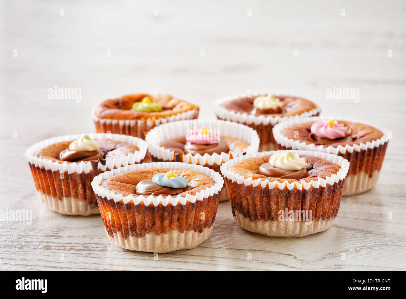 Sept faits maison délicieux mini cheesecakes avec du chocolat fondu et du sucre coloré arrose sur une table en bois Banque D'Images