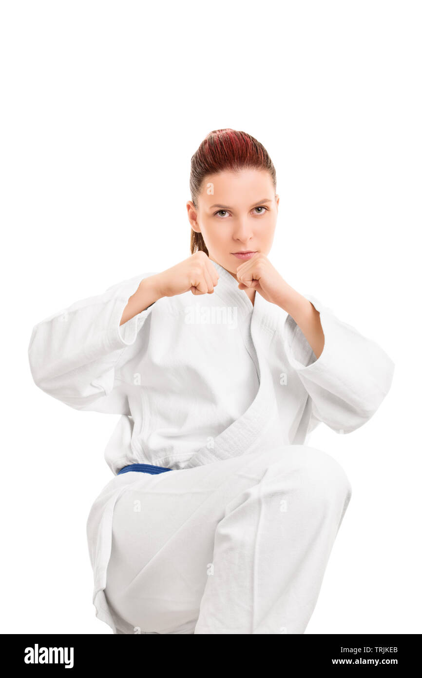 Un portrait d'une belle jeune fille belle en kimono avec une ceinture bleue, dans une position de combat pour préparer un coup de pied, isolé sur fond blanc. Banque D'Images