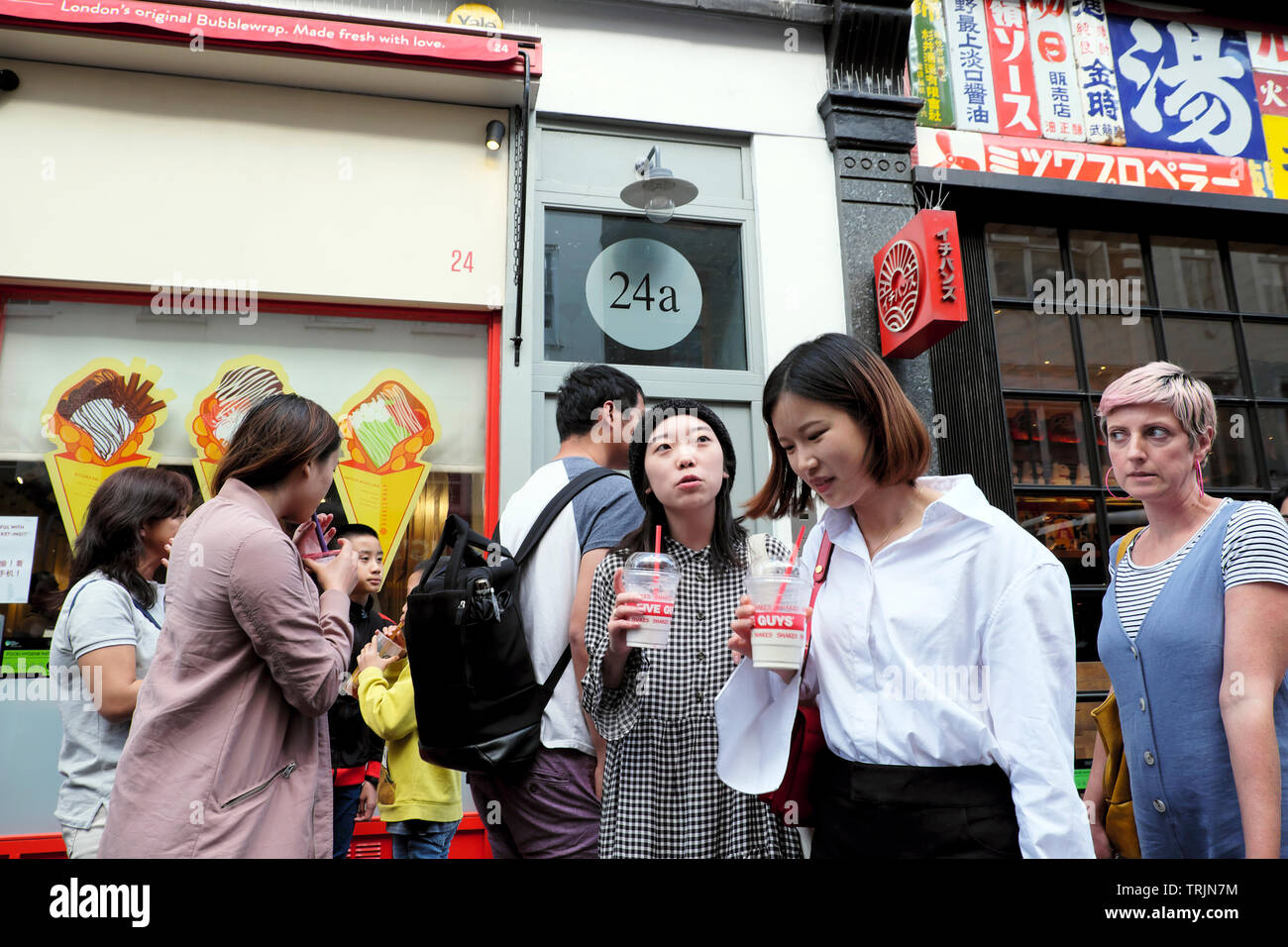 Chinois adolescents filles touristes sur Wardour Street boire secouer de Cinq Gars tasse en plastique et pailles visiter Chinatown Londres Angleterre Royaume-Uni KATHY DEWITT Banque D'Images