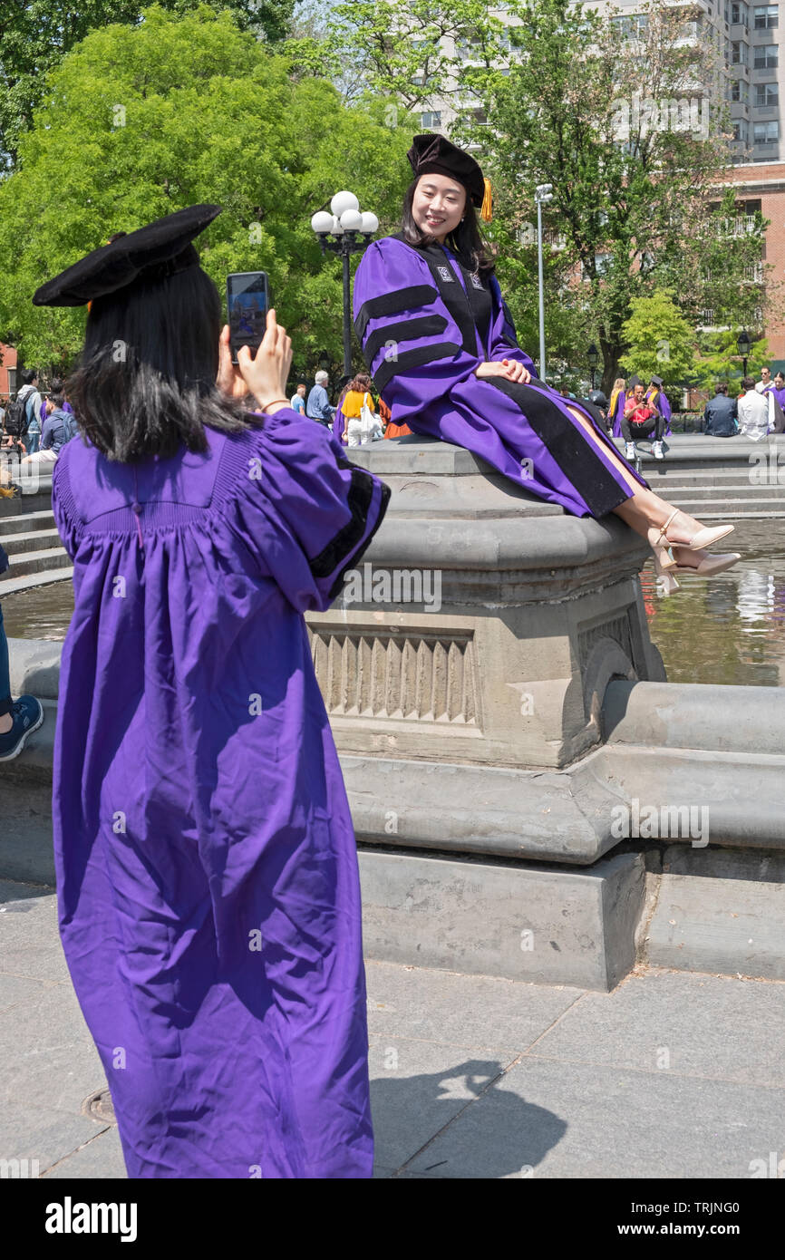 NYU sud-coréen de célébrer dans les diplômés du Washington Square Park prendre cell phone in leur casquette et des blouses. La ville de New York. Banque D'Images