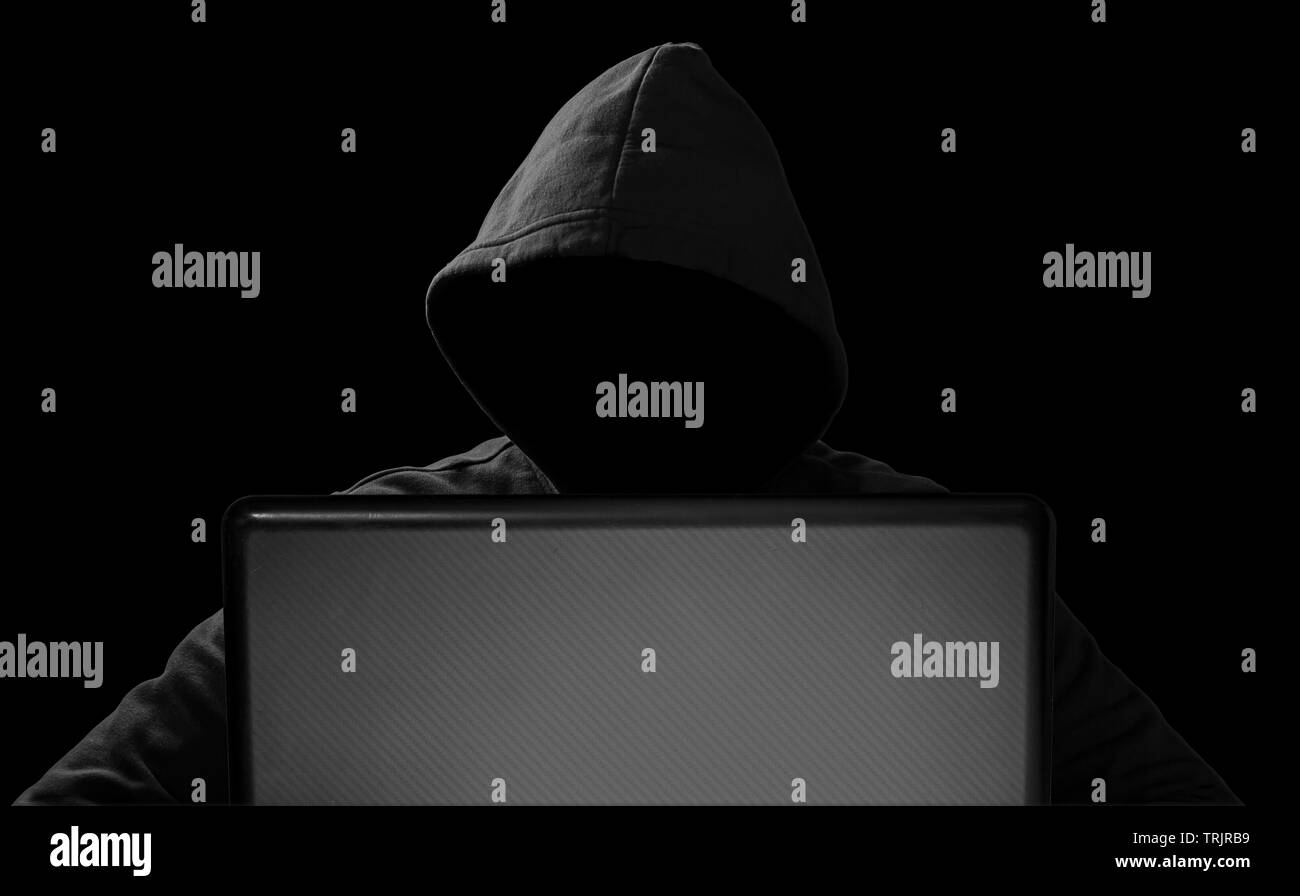Hacker avec un masque derrière l'ordinateur portable ordinateur portable en face de fond noir isolé internet cyber hack attack computer concept Banque D'Images
