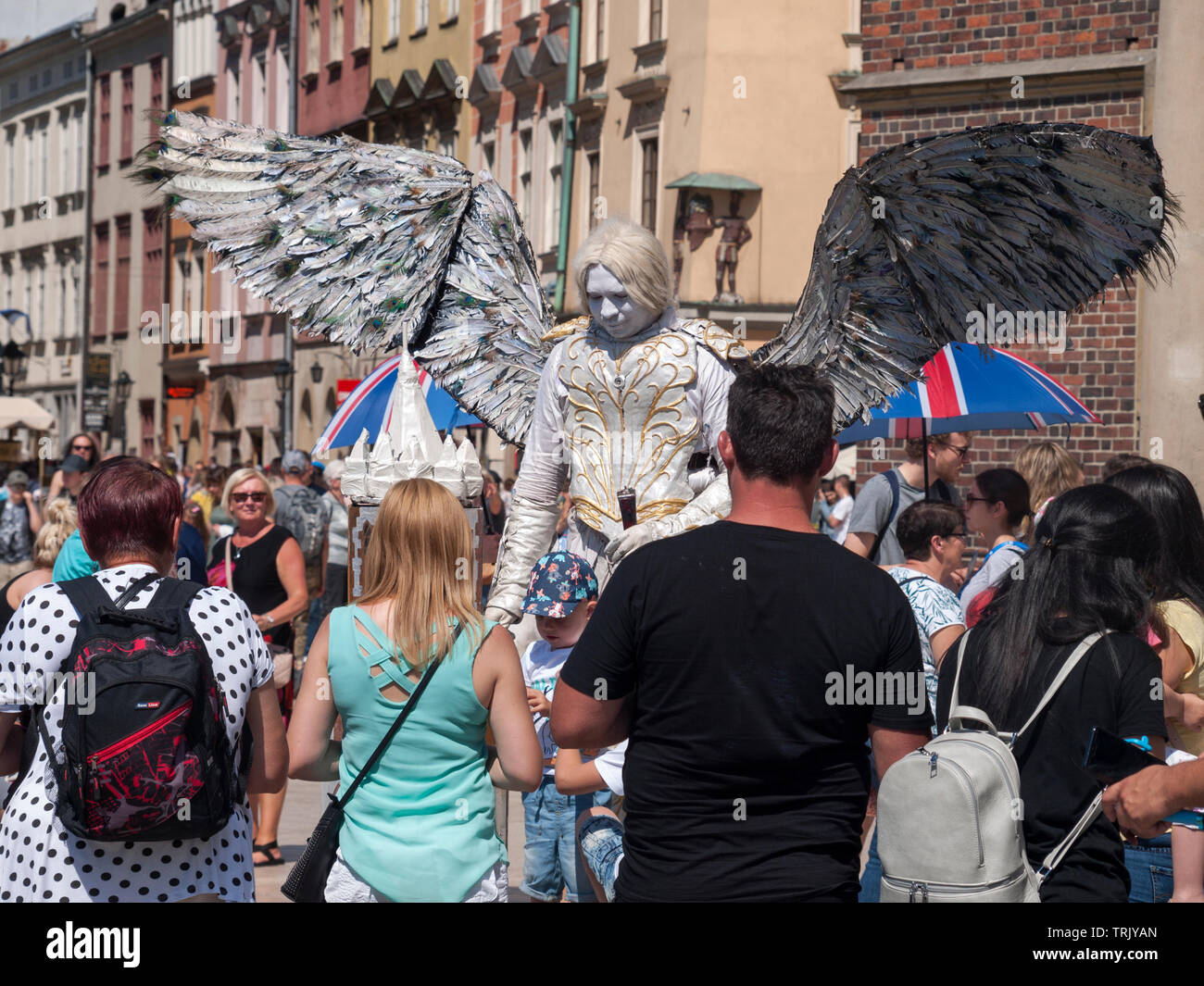 Musicien ambulant / Street performer habillé comme un ange avec des ailes, une énorme foule autour de lui l'attente pour prendre des photos. Arts de la rue, Banque D'Images