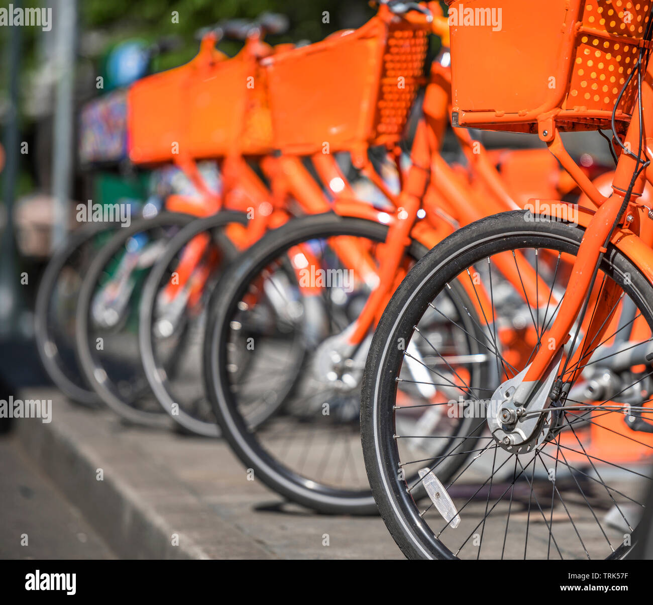 Transport des vélos de rue (orange avec panier de biens pour voyager autour de la ville dans la rangée stand sur réseau de location de stationnement en attente de Banque D'Images