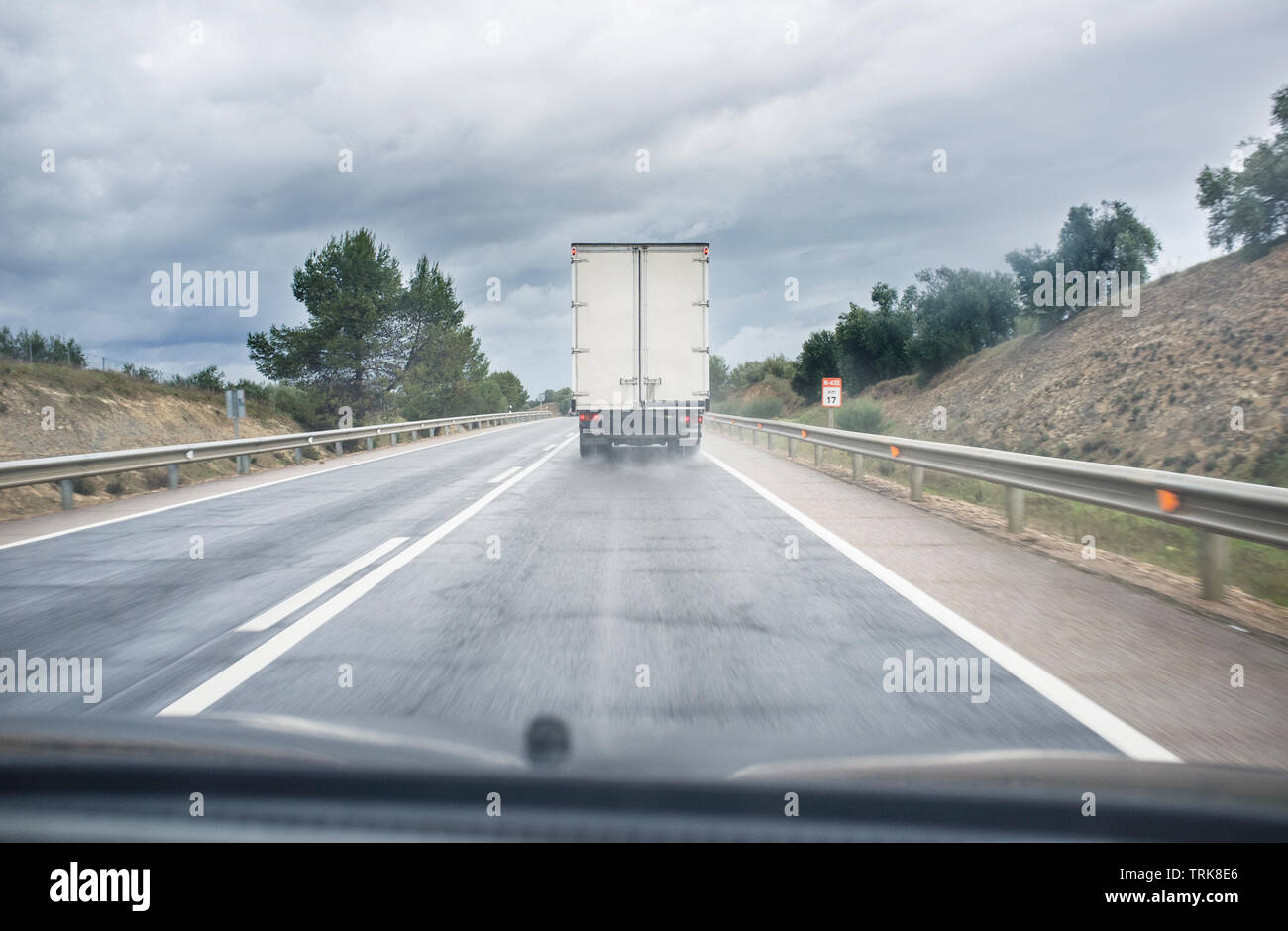 Derrière la conduite de camion lent sur la route un jour de pluie. Vue depuis l'intérieur de la voiture Banque D'Images