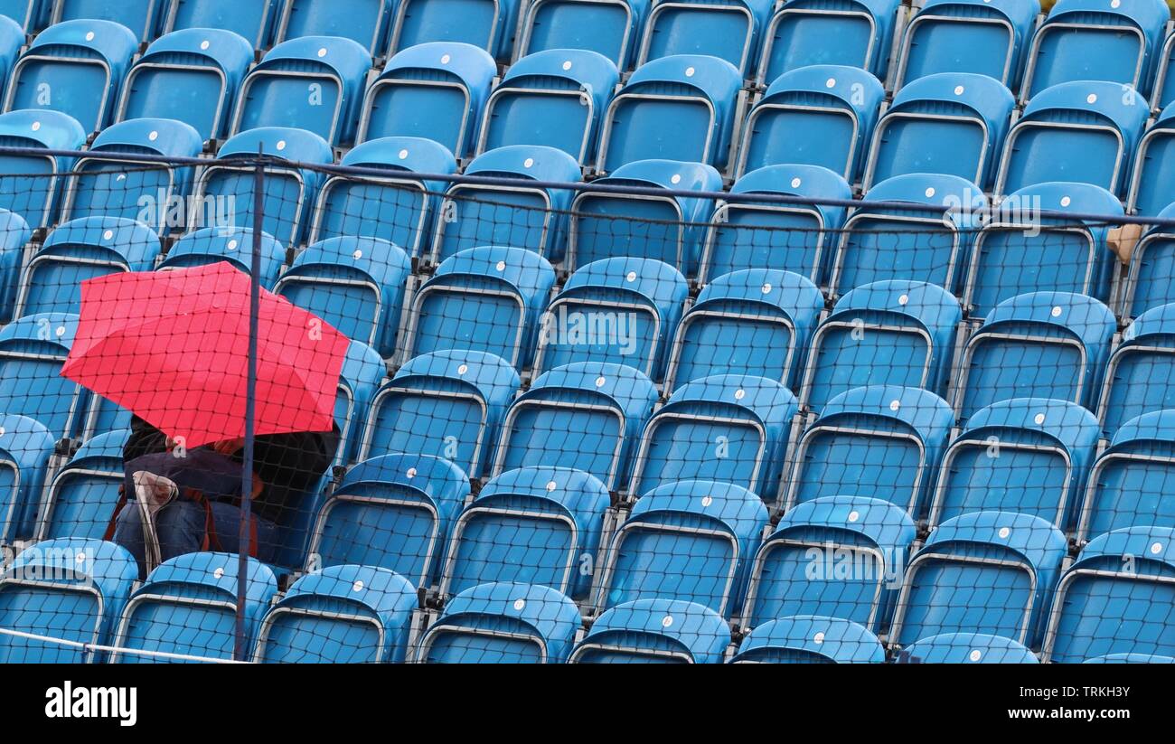 Surbiton, Londres : un ventilateur unique batailles la pluie dans l'espoir de voir certains action tennis plus tard dans la journée à la 2019 Trophée Surbiton. Banque D'Images