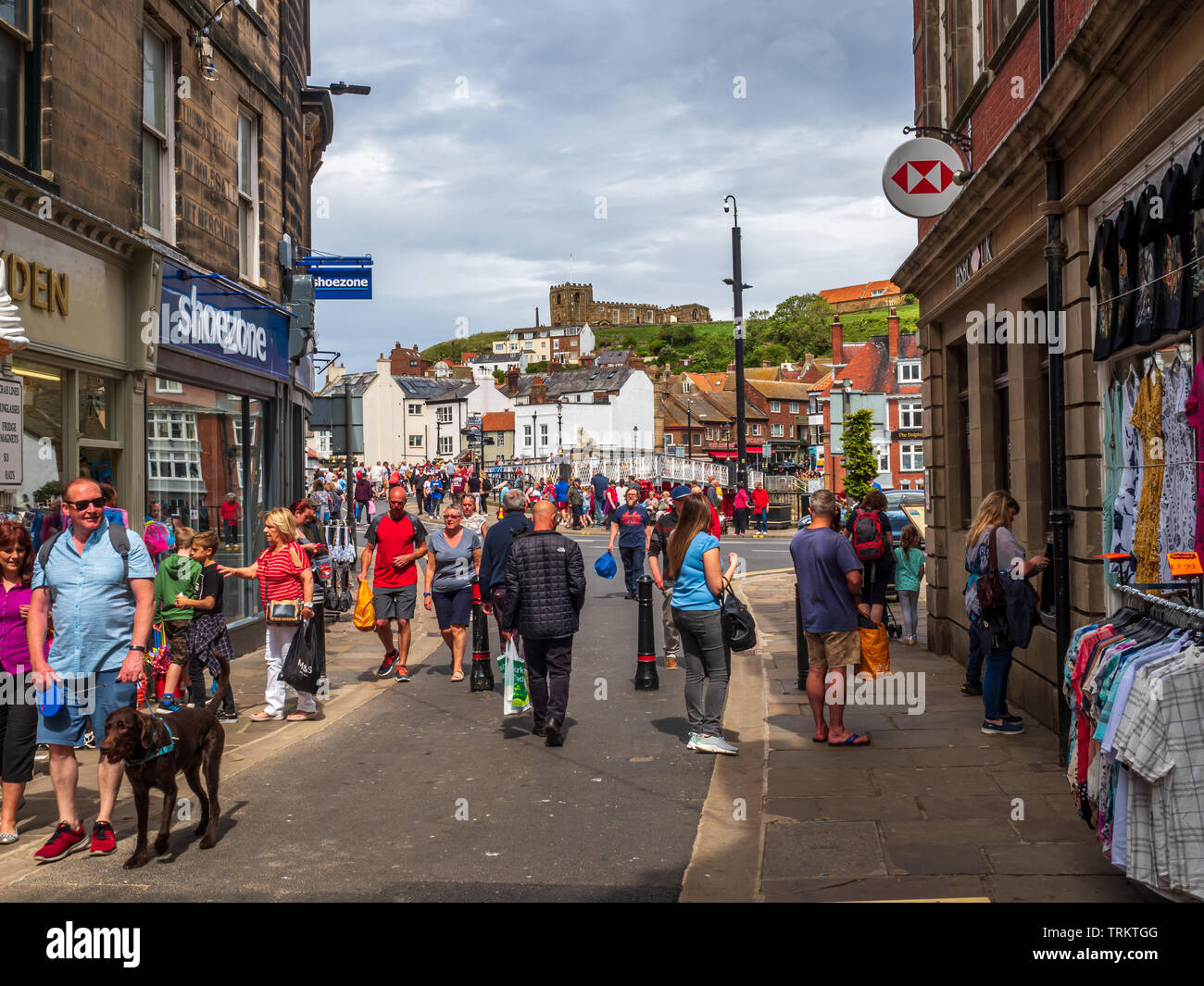 Rue commerçante animée de Whitby avec l'église St Mary en arrière-plan, des tronniers de touristes et de vacanciers affluent vers cette destination touristique populaire Banque D'Images