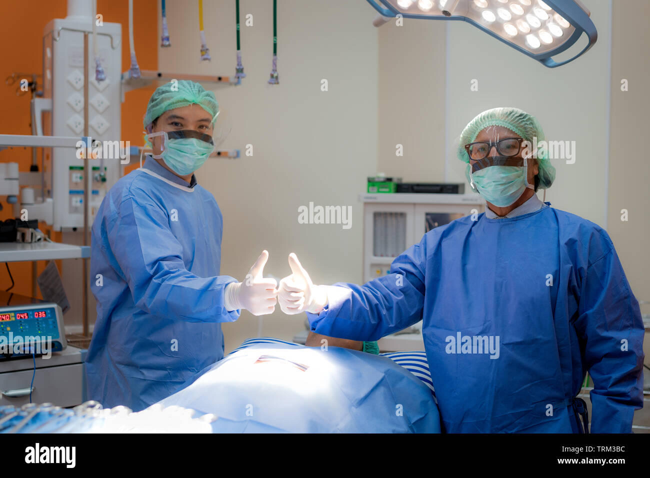 L'équipe de chirurgiens en uniforme et cultivés jusqu'à afficher le masque coup d'opération. L'équipe chirurgicale avant la chirurgie dans l'exploitation. Banque D'Images