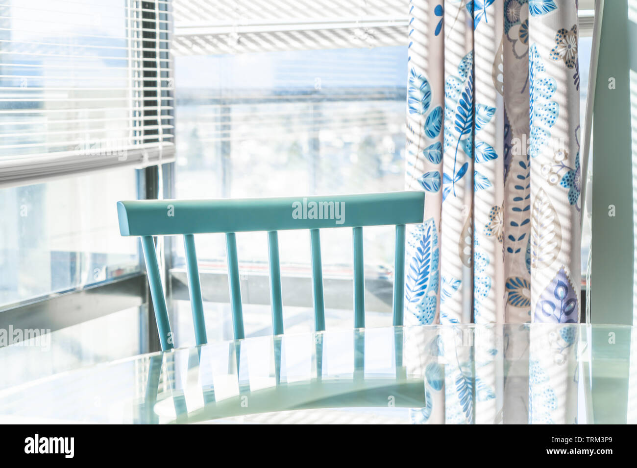 Coin repas lumineux contre une baie vitrée, avec un traditionnel bleu chaise et table en verre. Décoration d'appariement dans l'arrière-plan. Banque D'Images