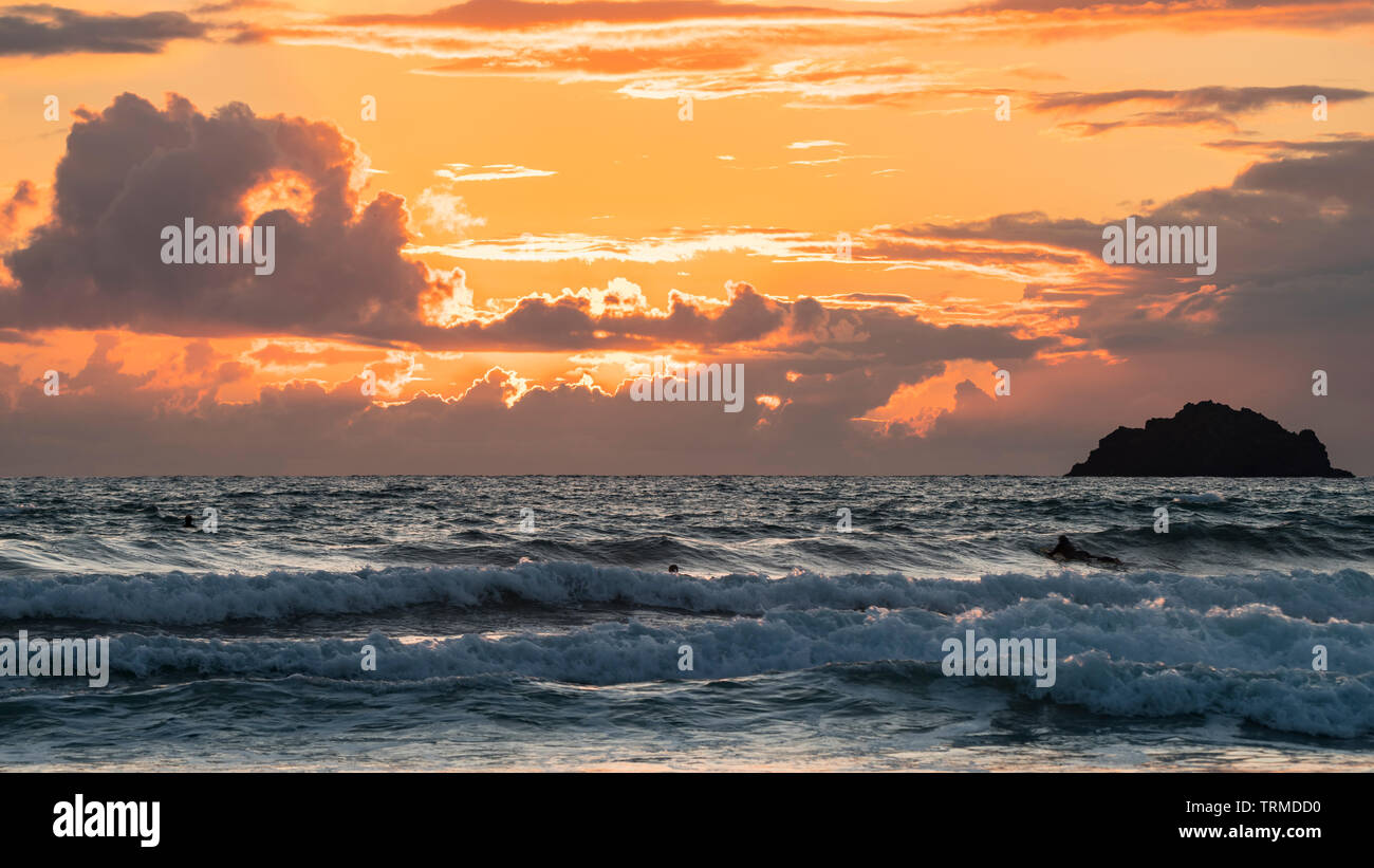Un ciel dramatique au crépuscule avec une orange d'incandescence et de sombres nuages au-dessus d'une mer agitée. Cornwall, UK. Banque D'Images