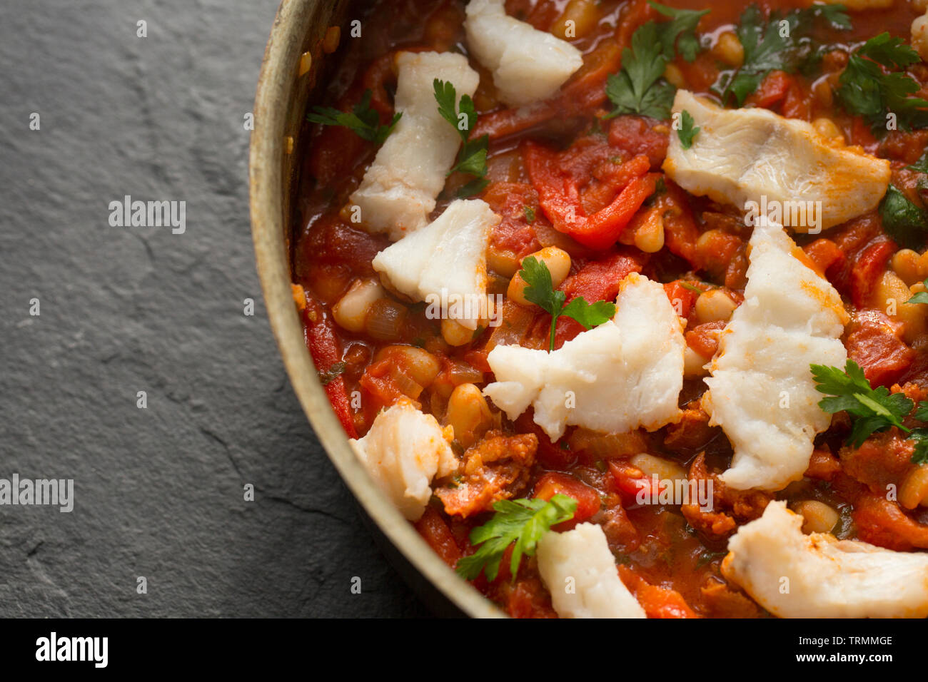 Un lieu jaune et chorizo ragoût de poisson avec des tomates, poivrons rouges grillés, les tomates en conserve, oignons, haricots CANNELLINI et le persil. T Banque D'Images