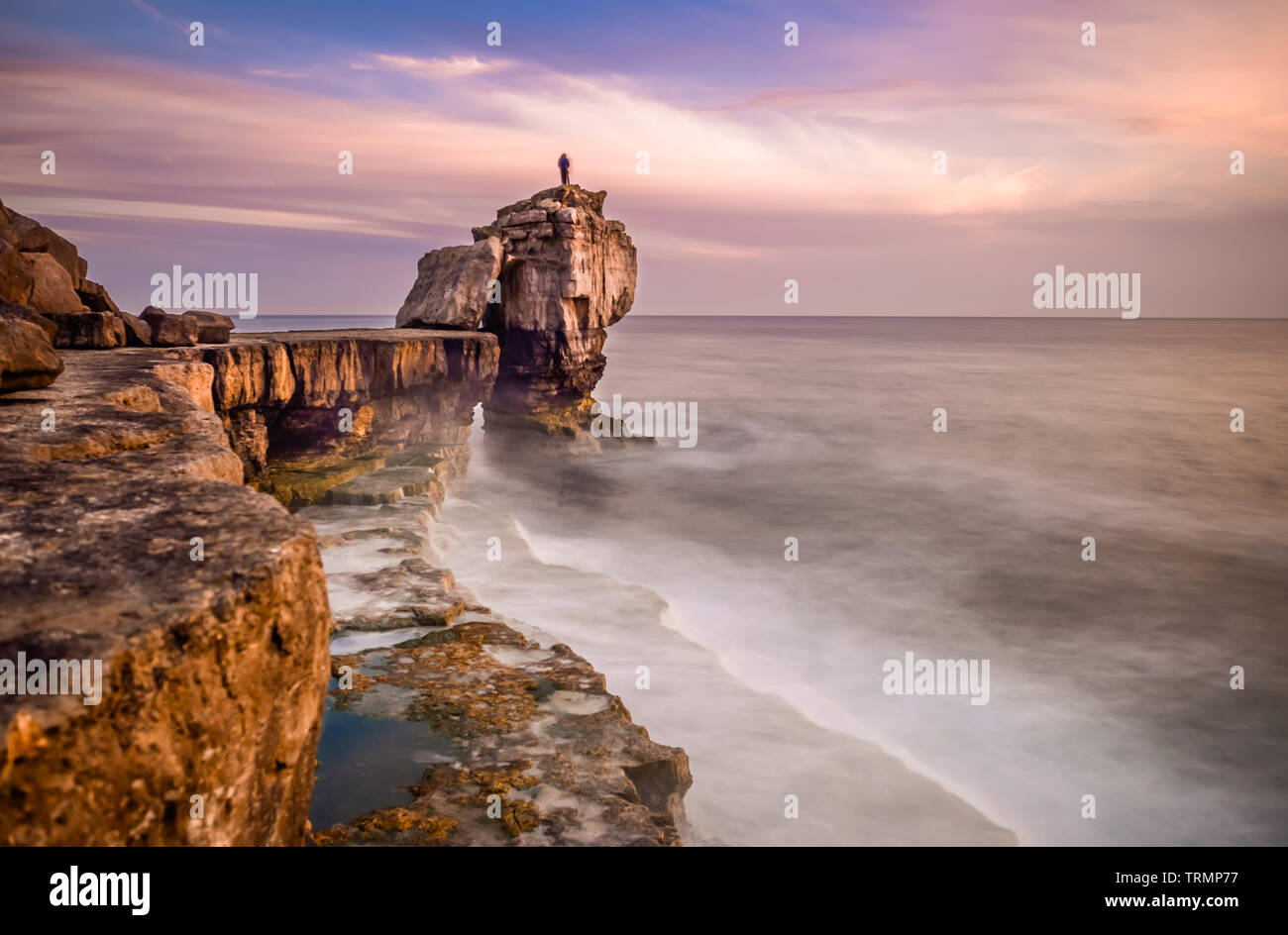 Homme debout sur le dessus de Pulpit Rock au coucher du soleil, Portland Bill sur l'Île de Portland près de Weymouth Dorset sur la côte jurassique. L'Angleterre. UK. Banque D'Images