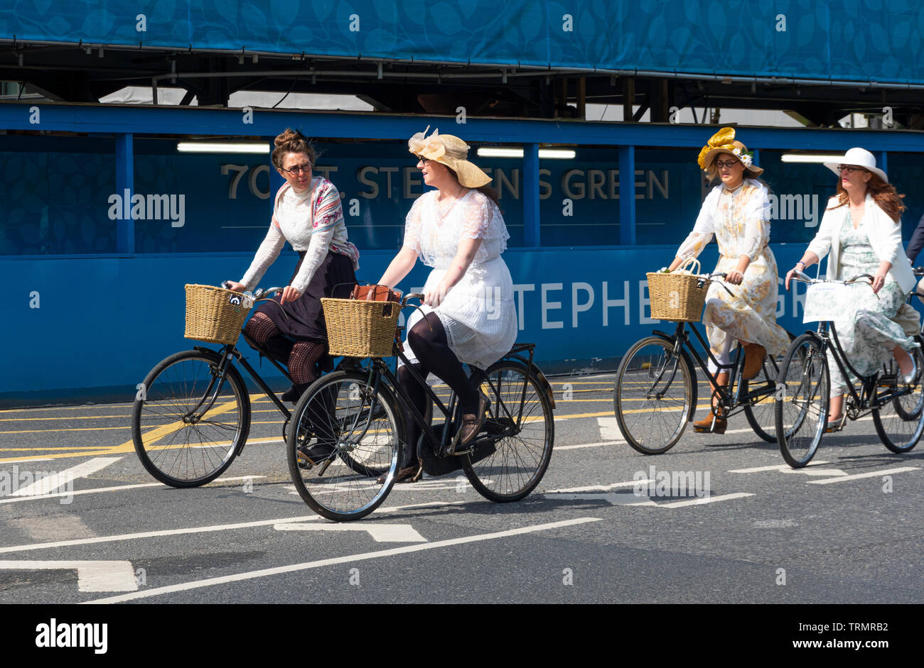 Les femmes irlandaises sur les bicyclettes dans Dublin​ ancien portant des robes et des chapeaux drôles Banque D'Images