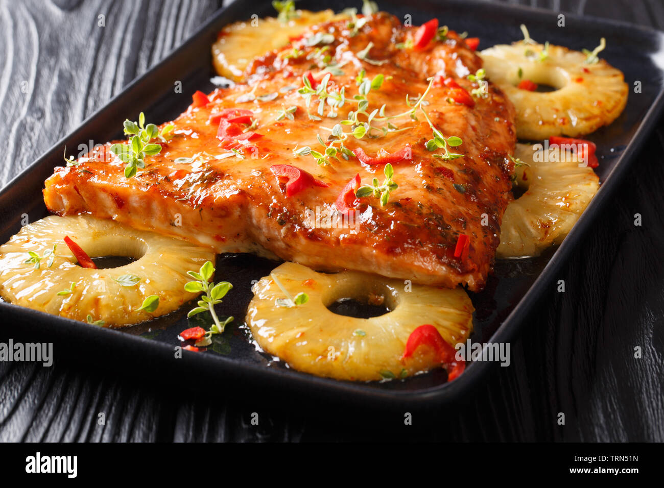 Plat de saumon avec une sauce douce et épicée et ananas juteux gros plan sur une assiette sur la table horizontale. Banque D'Images