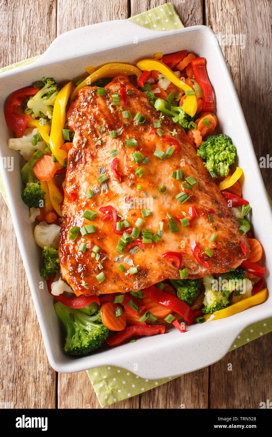 Filet de poisson rouge cuit avec les légumes, épices et fines herbes close-up dans un plat allant au four, sur la table. Haut Vertical Vue de dessus Banque D'Images