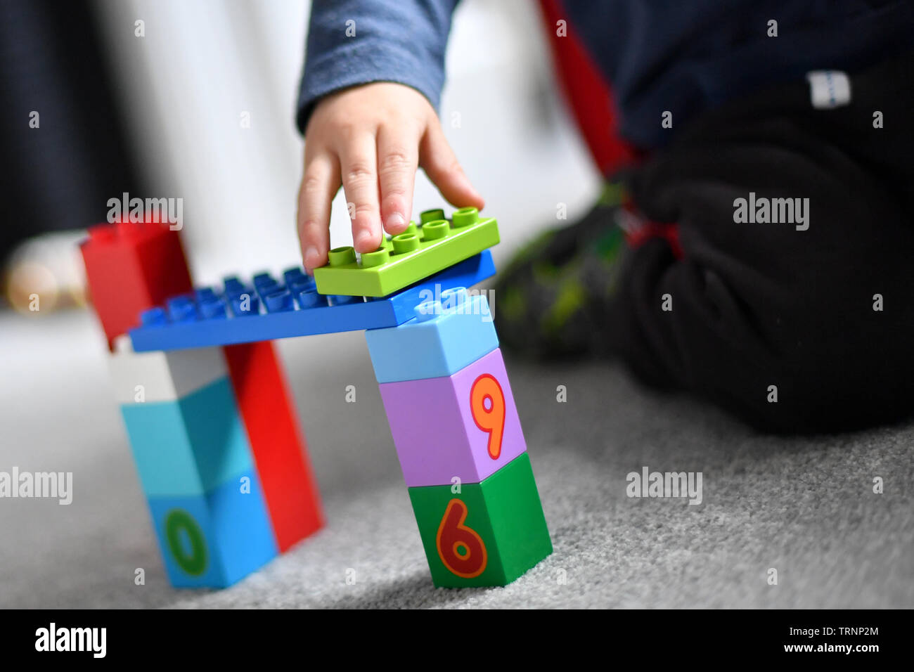 Un garçon en robe d'un capuchon et le masque joue avec des blocs Lego Duplo Banque D'Images