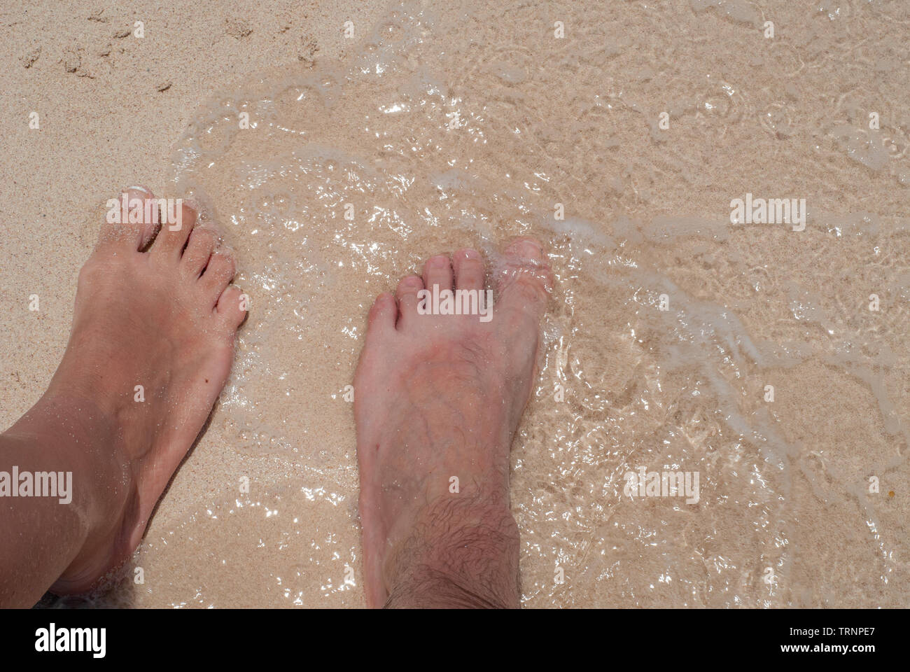 Pieds de deux amoureux dans les vagues et le sable, prise à Tulum dans la péninsule mexicaine du Yucatan Banque D'Images