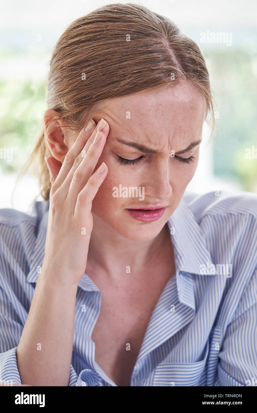 Femme a souligné la souffrance avec maux de tête In Office Banque D'Images
