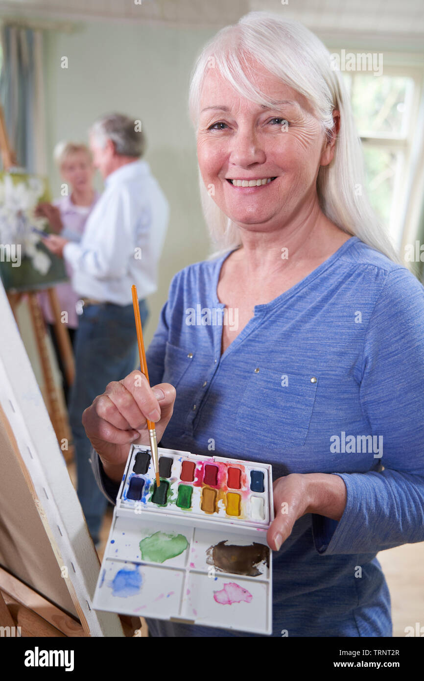 Portrait of Senior Woman assistant à classe de peinture avec l'enseignant en arrière-plan Banque D'Images