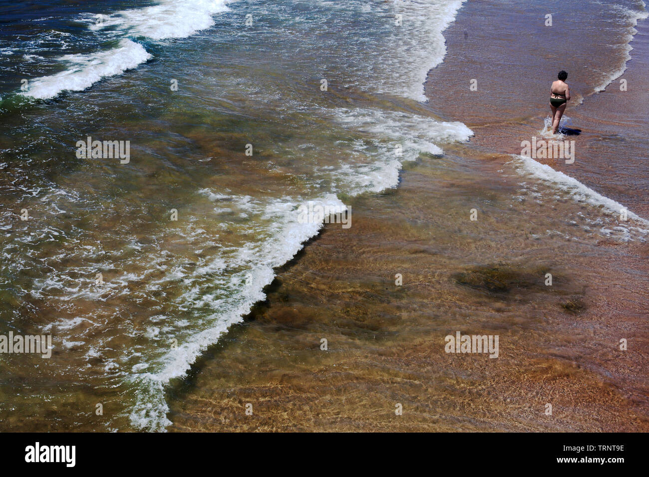 Femme de patauger dans la mer à son smartphone. Banque D'Images