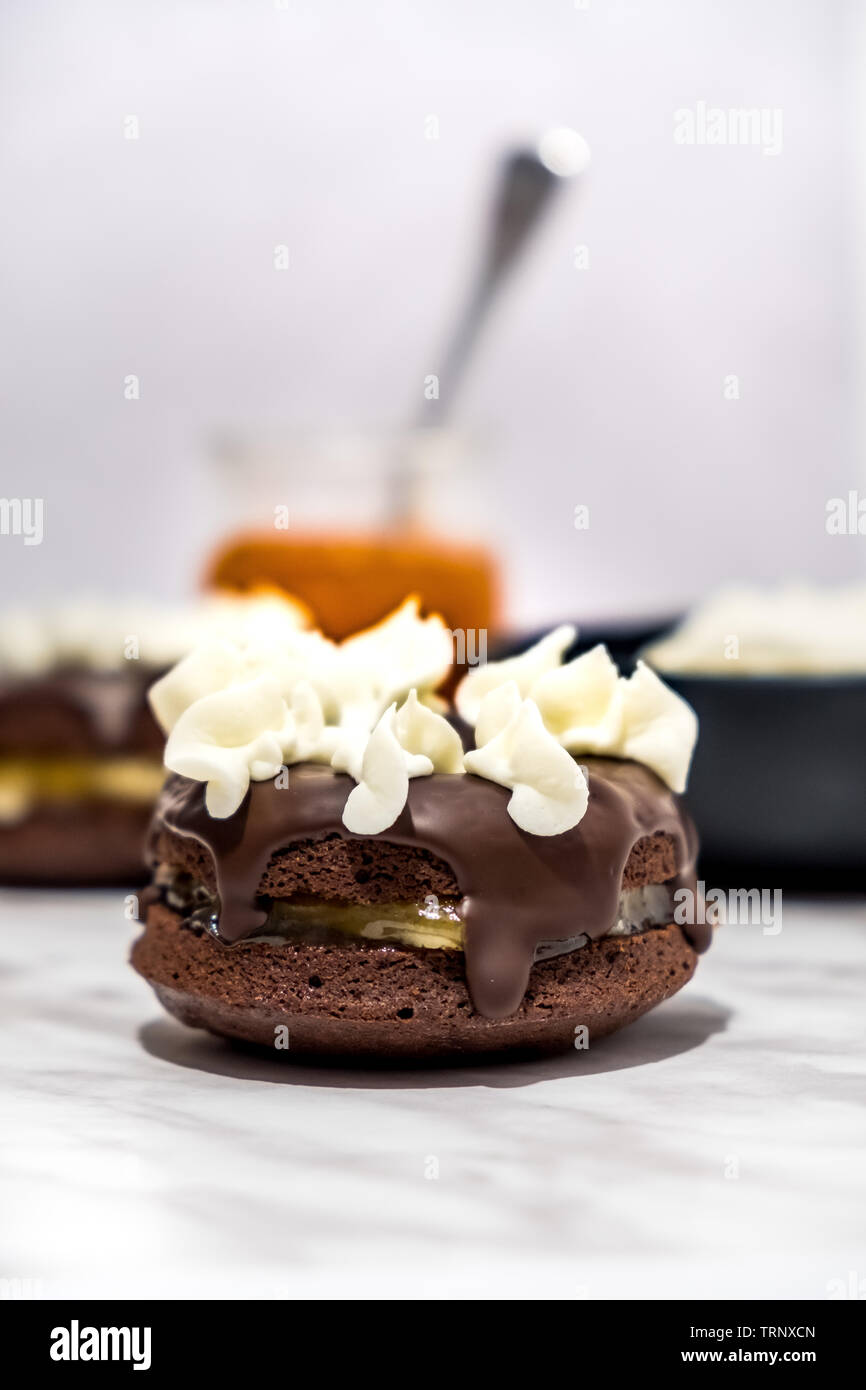 Le style viennois Sachertorte (gâteau) Donut avec confiture d'abricot et d'Amandes au centre, recouvert de chocolat fondu, décoré avec de la crème fouettée Banque D'Images