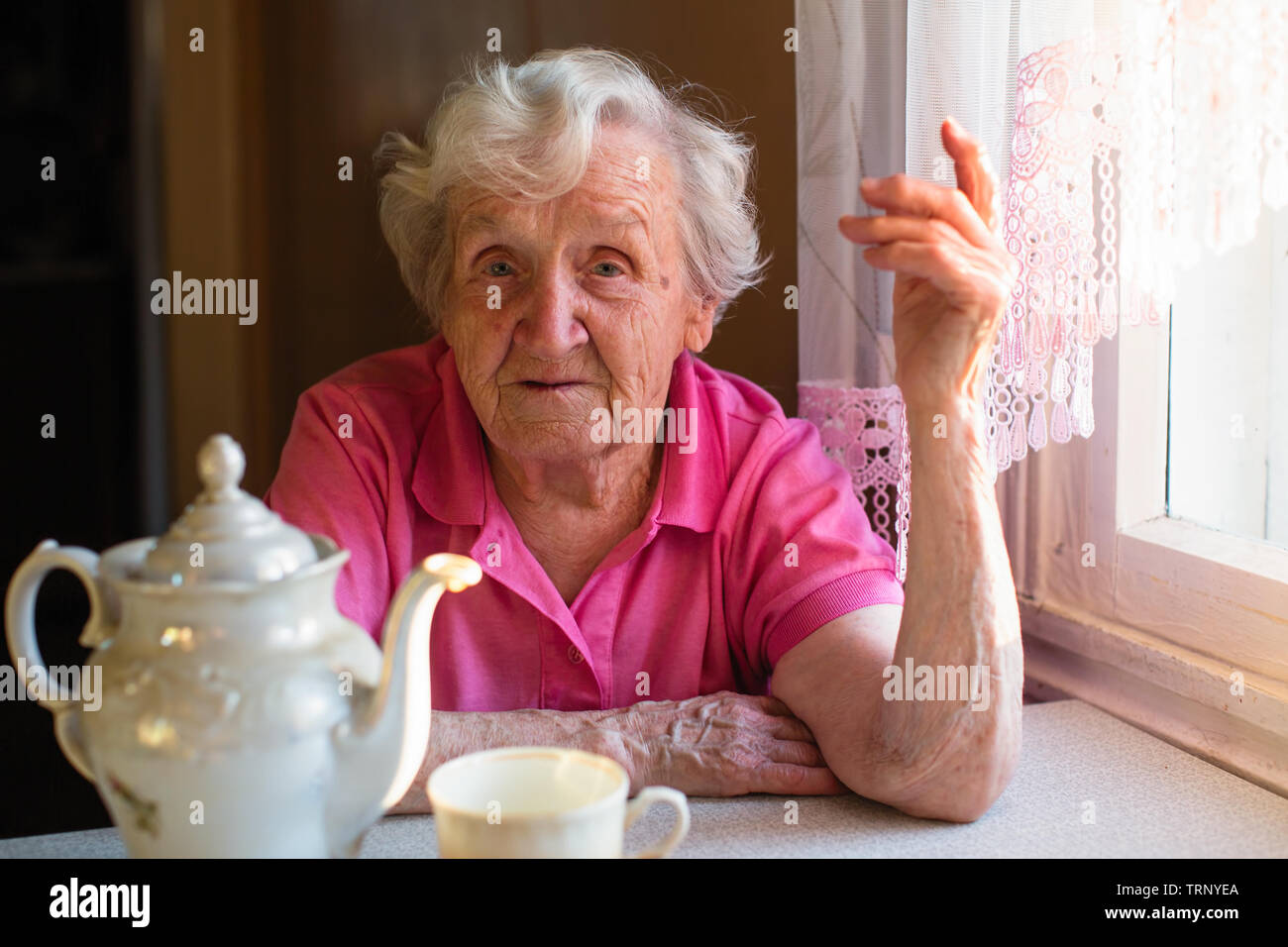 Portrait d'une femme âgée assise à la table de la cuisine. Banque D'Images