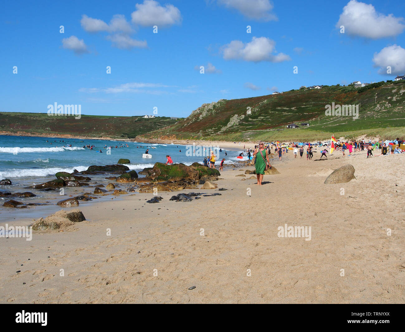 Les gens appréciant une journée d'été ensoleillée sur la plage de Sennen Cove, Cornwall, Angleterre, Royaume-Uni avec la plage de sable et la mer bleue sous un ciel bleu. Banque D'Images