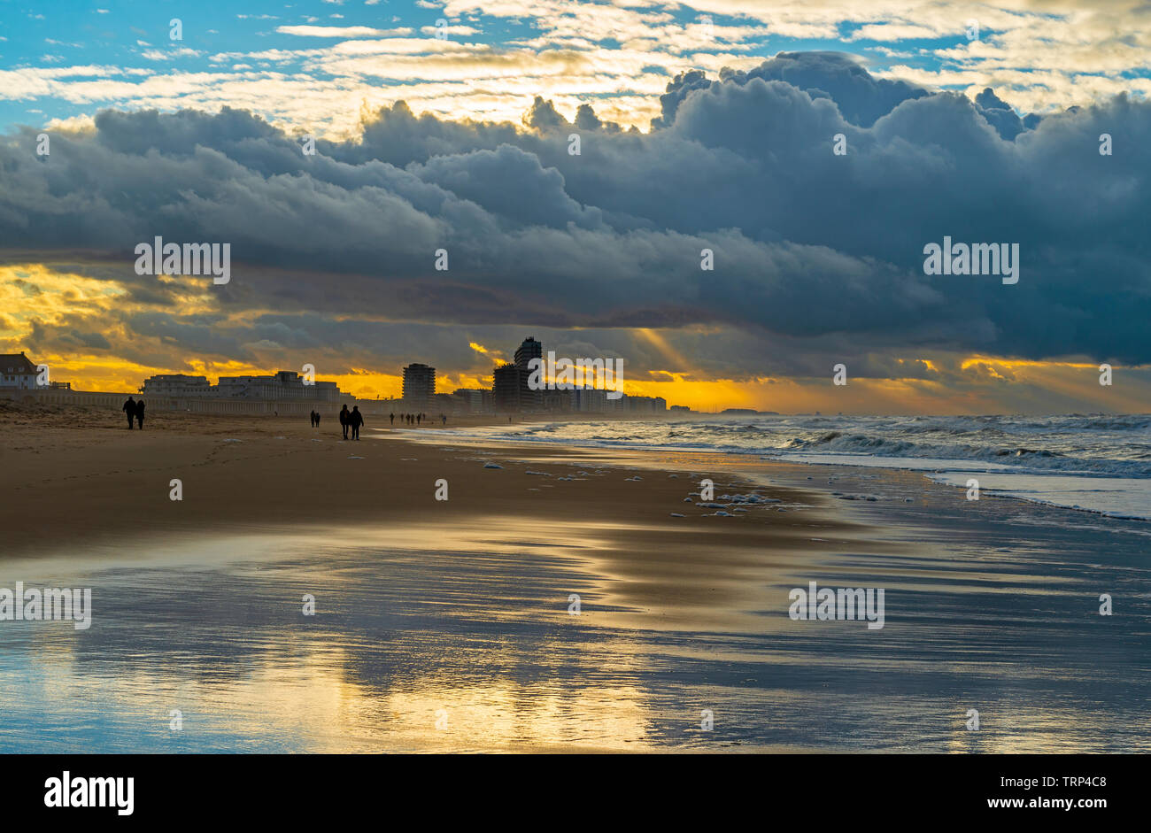 La silhouette de personnes marchant sur la plage de la mer du Nord d'Oostende ville au coucher du soleil, Flandre occidentale, Belgique. Banque D'Images