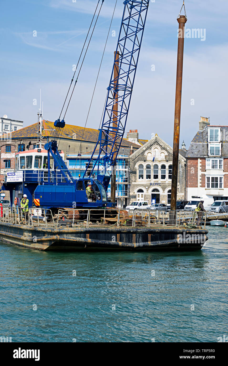 Vue Portrait d'une barge de pieux automoteur se déplace en position pour insérer l'empilage pour les travaux de construction du port de Weymouth. Banque D'Images