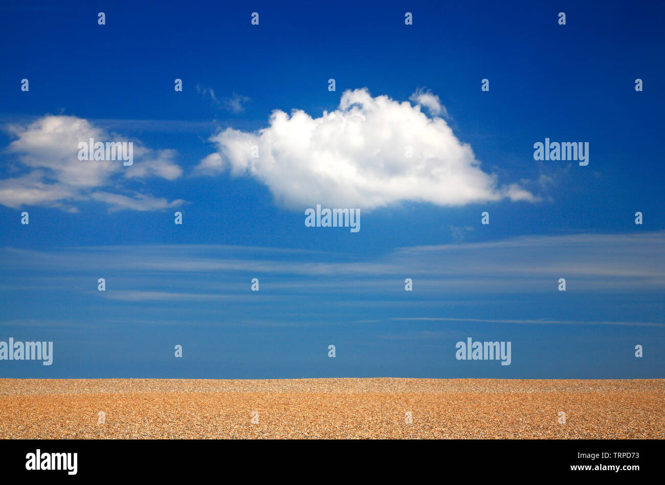 Un grand nuage blanc contre un ciel bleu au-dessus d'une crête de galets sur la côte nord du comté de Norfolk à Salthouse, Norfolk, Angleterre, Royaume-Uni, Europe. Banque D'Images