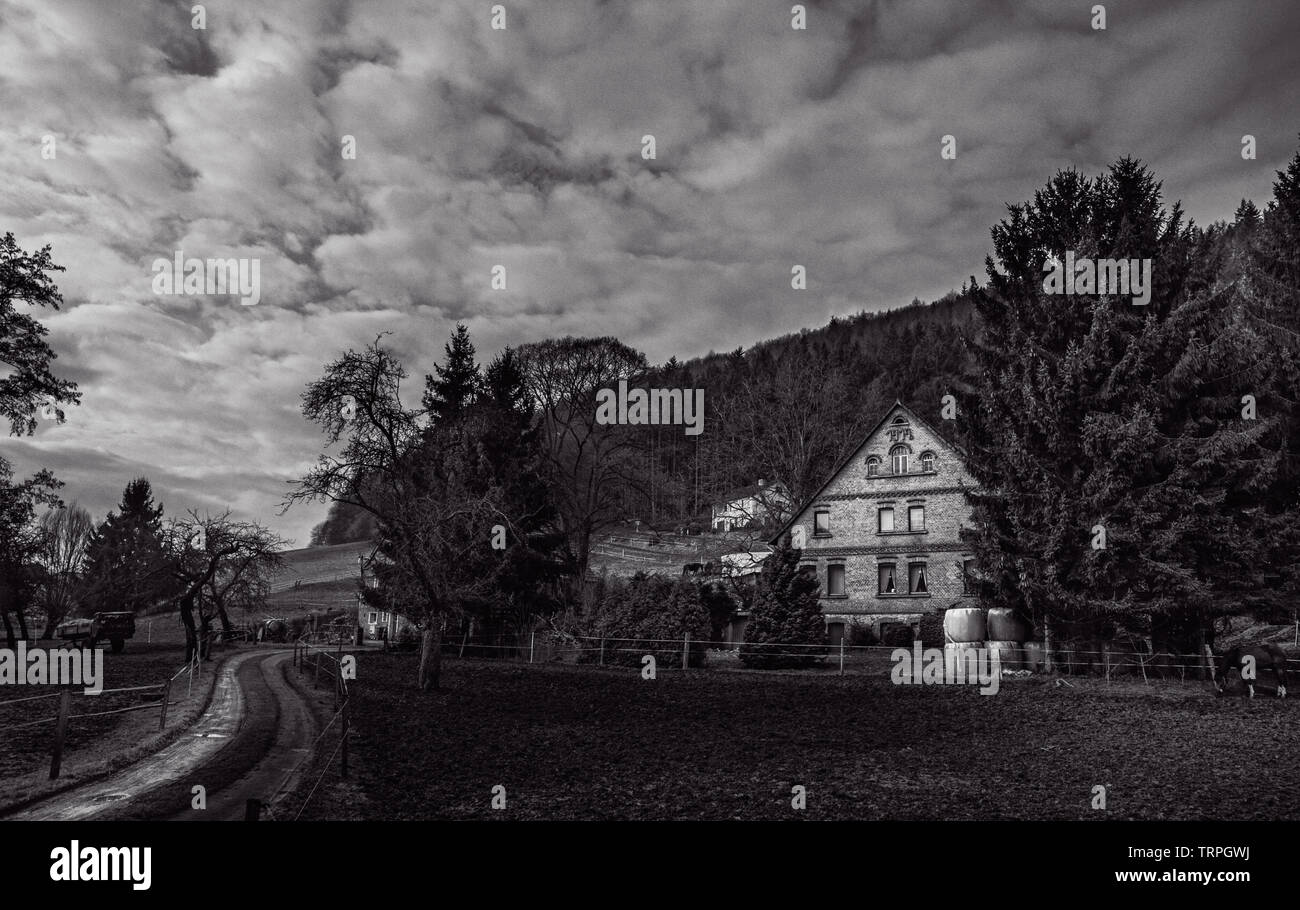 Un paysage du village d'Allemagne en noir et blanc avec un maquereau ciel au-dessus et une route sinueuse menant à la maison d'une belle architecture. Banque D'Images Un paysage du village d'Allemagne en noir et blanc avec un maquereau ciel au-dessus et une route sinueuse menant à la maison d'une belle architecture. Banque D'Images
